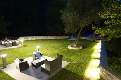 a garden at night with chairs and a tree at Les Jardins De La Glacière in Corte