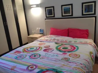a bed with a colorful comforter and red pillows at Porto-Vecchio Baie Santa Giulia appartement une chambre 4-5 personnes in Porto-Vecchio