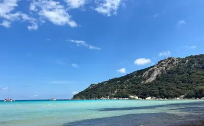 a view of a beach with a mountain in the background at Porto-Vecchio Baie Santa Giulia appartement une chambre 4-5 personnes in Porto-Vecchio