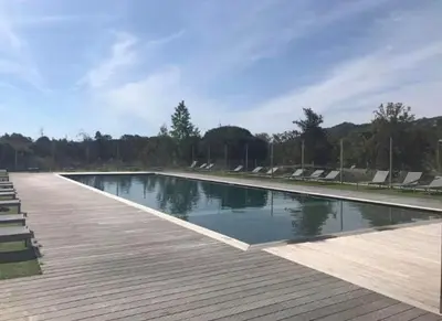 a swimming pool with chairs and a wooden deck at Porto-Vecchio Baie Santa Giulia appartement une chambre 4-5 personnes in Porto-Vecchio