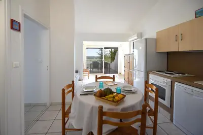 a kitchen with a table with a bowl of fruit on it at Résidence Chiar' Di Luna in Sainte-Lucie de Porto-Vecchio