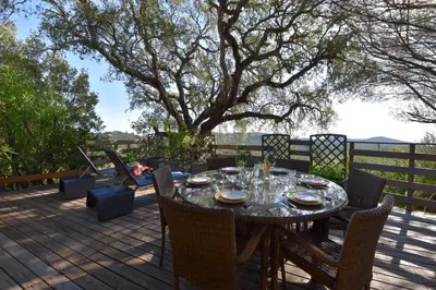 a table and chairs on a deck with a tree at Résidence Chiar' Di Luna in Sainte-Lucie de Porto-Vecchio