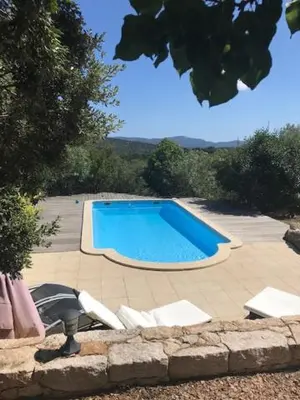 a swimming pool with white chairs and a blue at Maison Ferruccio in Porto-Vecchio