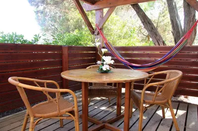 a wooden table and chairs on a deck with a hammock at Résidence Mobydick in Porto-Vecchio