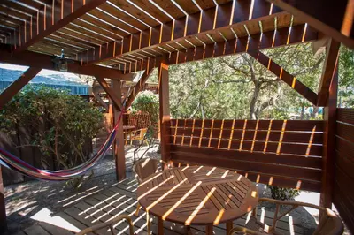 a wooden pergola with a bench and a hammock at Résidence Mobydick in Porto-Vecchio