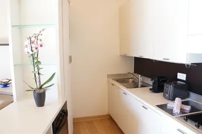 a kitchen with white cabinets and a vase of flowers on the counter at Résidence Cala Sultana in Porto-Vecchio