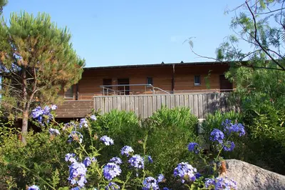 a house behind a fence with purple flowers at Résidence Cala Sultana in Porto-Vecchio