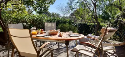 a wooden table and chairs on a patio at Résidence Cala Sultana in Porto-Vecchio