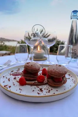 a plate with cookies and raspberries on a table with glasses at Hôtel & Lodges Moby Dick in Porto-Vecchio