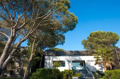a house with trees in front of it at Hôtel & Lodges Moby Dick in Porto-Vecchio