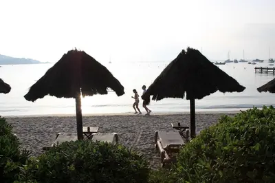 a person running on a beach with umbrellas at Hôtel & Lodges Moby Dick in Porto-Vecchio