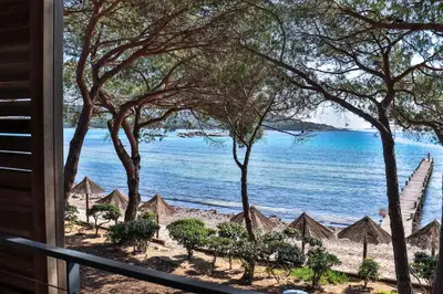 a view of a beach with umbrellas and the ocean at Hôtel & Lodges Moby Dick in Porto-Vecchio