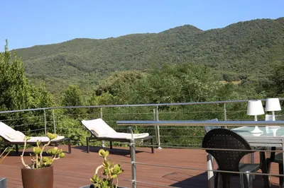 two chairs and a table on a deck with mountains in the background at Casa Giacometti in Grosseto-Prugna