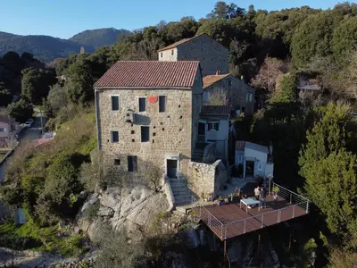 an old stone house on a hill with a deck at Casa Giacometti in Grosseto-Prugna