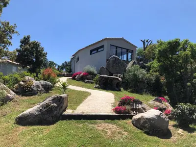 a garden with rocks and a house in the background at A Camerina in Sotta