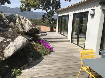 a wooden deck with a table and chairs and flowers at A Camerina in Sotta