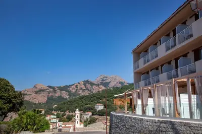 a view of a building with mountains in the background at Hotel Scandola in Piana
