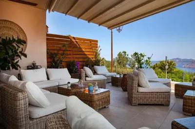 a patio with wicker chairs and couches and a view at Hotel Scandola in Piana
