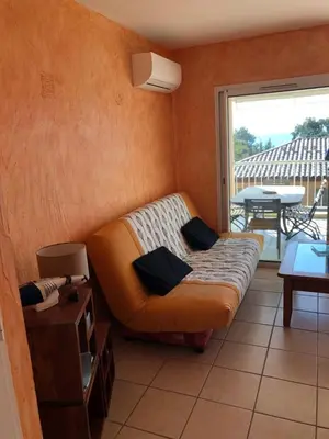 a couch sitting in a living room with a balcony at PORTICCIO, AGOSTA PLAGE vue mer pour 6 p, 2 ch, PROMO 7 nuits in Porticcio
