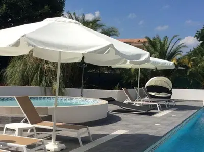 a group of chairs and umbrellas next to a pool at Villa in Moriani-Plage near Sandy Beach in San-Nicolao