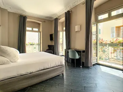 a bedroom with a bed and a desk and a window at Hotel POZZO DI BORGO in Ajaccio