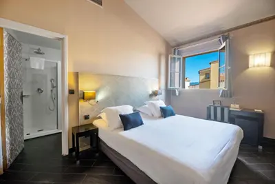 a bedroom with a large white bed and a window at Hotel POZZO DI BORGO in Ajaccio