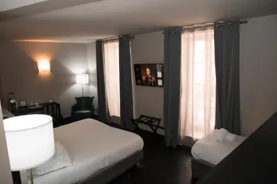 a hotel room with two beds and a window at Hotel POZZO DI BORGO in Ajaccio
