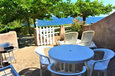 a blue table and chairs with the ocean in the background at CANELLA 2 in Favone