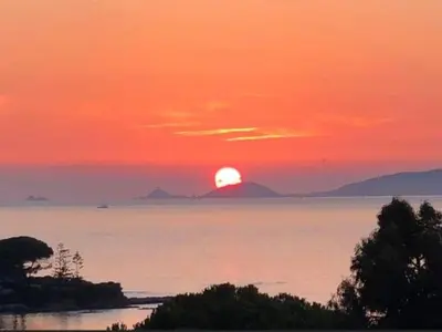 a sunset over the water with the sun in the sky at duplex vue mer exceptionnelle in Porticcio