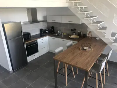 a kitchen with a wooden table and a refrigerator at duplex vue mer exceptionnelle in Porticcio