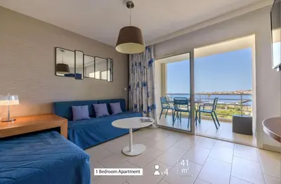 a living room with a blue bed and a table and chairs at Best Western Plus Ajaccio Amirauté in Ajaccio