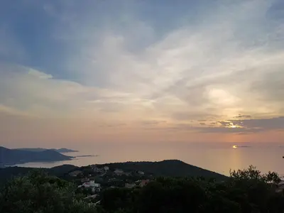 a sunset over the water and a town on a hill at Villa Gasparini in Pietrosella
