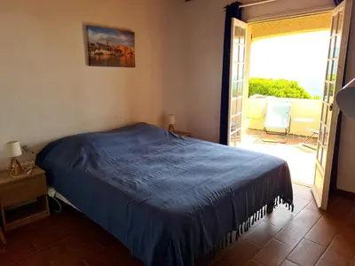 a bedroom with a blue bed and a balcony at Villa Gasparini in Pietrosella