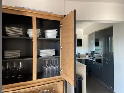 a kitchen with a wooden cabinet with plates and glasses at Le Haut de la Vague in Porto-Vecchio