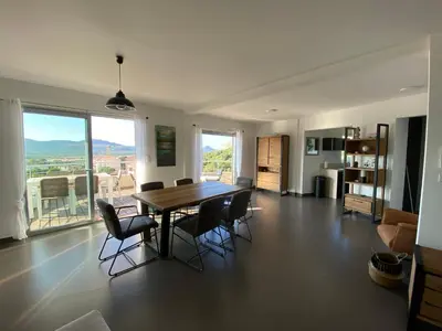 a living room with a dining room table and chairs at Le Haut de la Vague in Porto-Vecchio