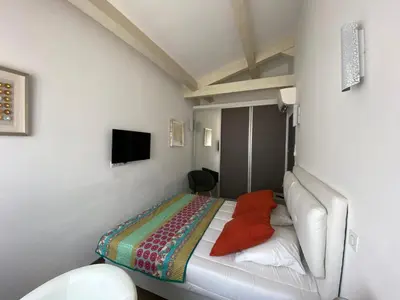 a small bedroom with a bed and a tv at Le Haut de la Vague in Porto-Vecchio