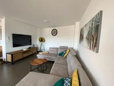 a living room with a couch and a tv at Le Haut de la Vague in Porto-Vecchio