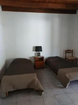 two beds in a room with a table and a lamp at U Palmu in Sagone