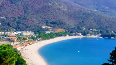 a view of a beach with blue water and mountains at U Palmu in Sagone
