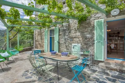 a patio with a table and chairs and a stone wall at Casa La Colombaia in Poggio-di-Nazza