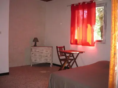 a bedroom with a table and a chair and a window at Residence U Veniqui in Favone