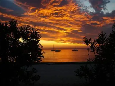a sunset over the ocean with boats in the water at Residence U Veniqui in Favone