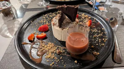 a chocolate dessert on a black plate with a drink at Residence U Veniqui in Favone