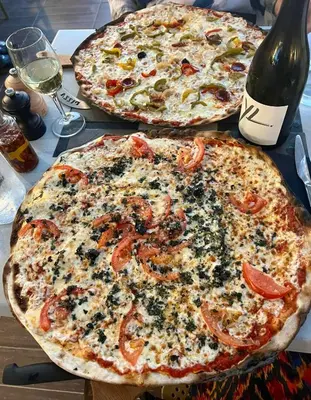 two pizzas sitting on a table with a bottle of wine at Residence U Veniqui in Favone