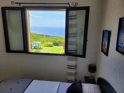 a bedroom with a window with a view of a yard at Villa Acqua Doria in Coti-Chiavari