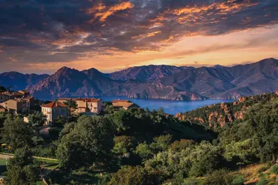 a town on a hill with a lake and mountains at Hôtel Mare E Monti in Piana
