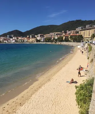 a beach with people laying on the sand and the water at Au cœur de la Vieille Ville in Ajaccio