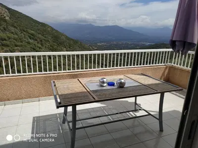 a table on a balcony with a view of the mountains at ELI&LOU avec piscine in Alata