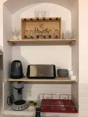 a kitchen with a shelf with glasses and a microwave at Studio plein centre ville in Ajaccio