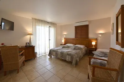 a bedroom with a bed and a desk and a window at Hôtel A casa di Maria Cicilia in Ghisonaccia
